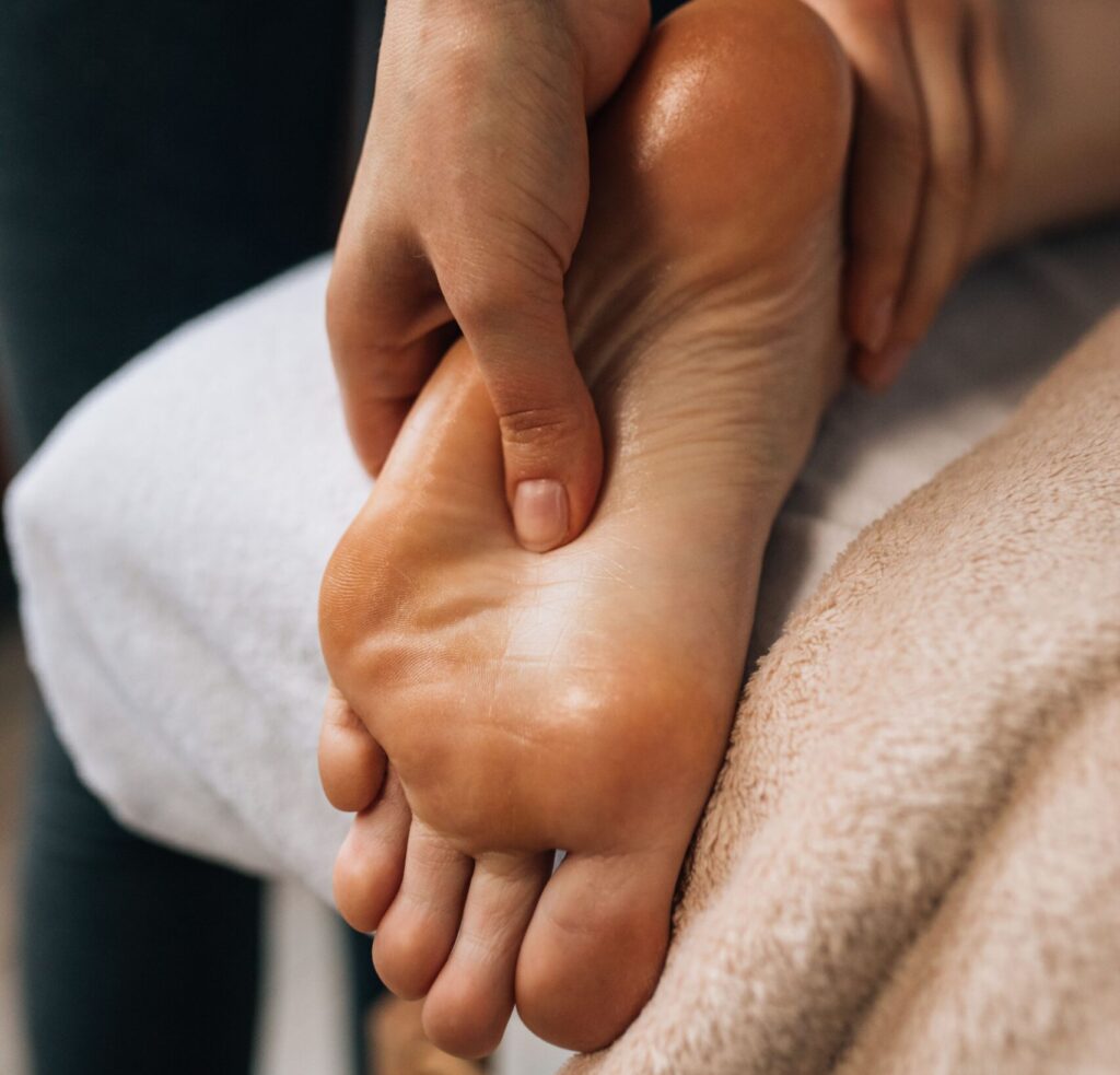 Hands massaging a foot to provide relaxation and promote wellness indoors.